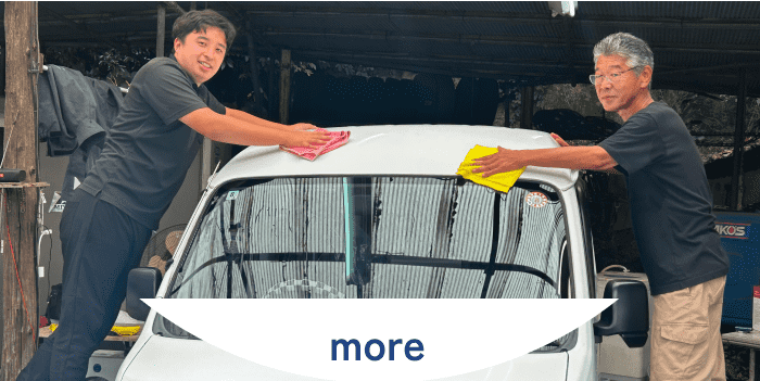 年齢の異なる二人の男性が協力して軽トラックを手洗いしている風景