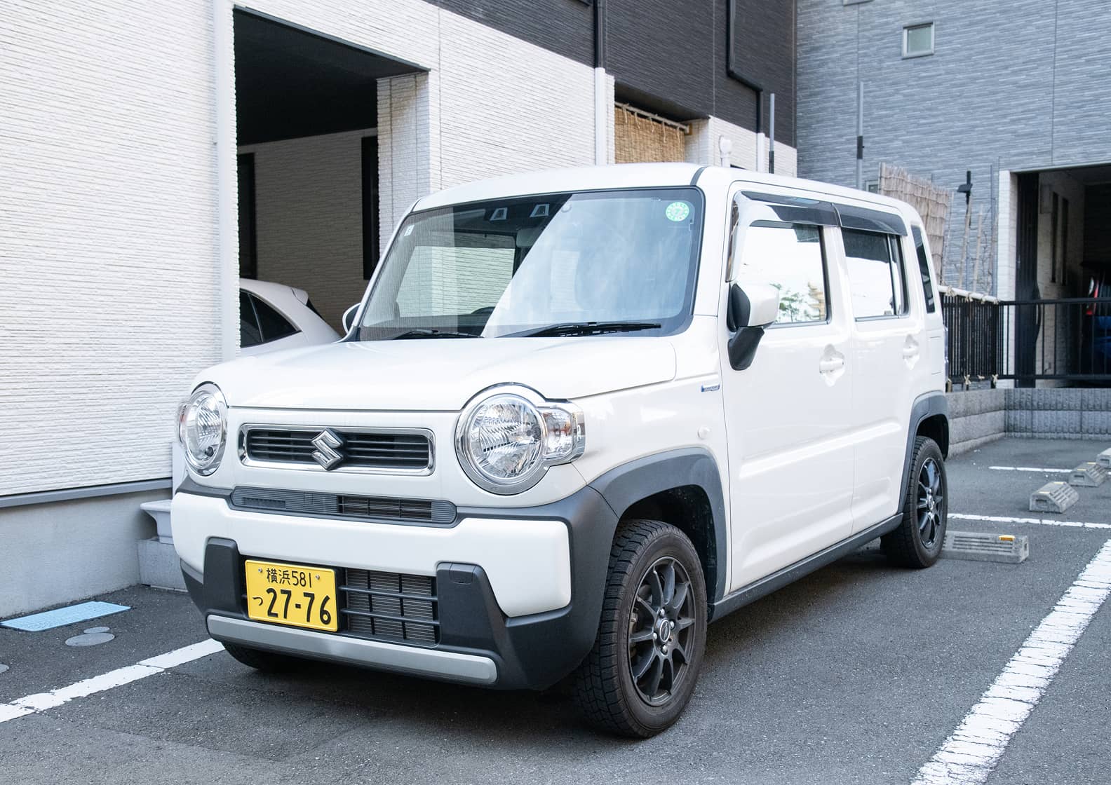 訪問診療に使用される白い軽自動車（スズキ・ハスラー）の全景。駐車場に停まっており、清潔感のある外観です。機材の積み下ろしがしやすい形状で、茅ヶ崎周辺の細い道でもスムーズに移動できる車両です。