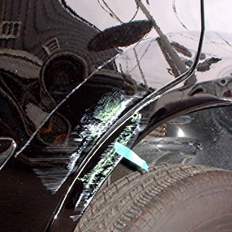 動車の側面を修理中の様子で、塗装前の下地処理が施された黒い車体。