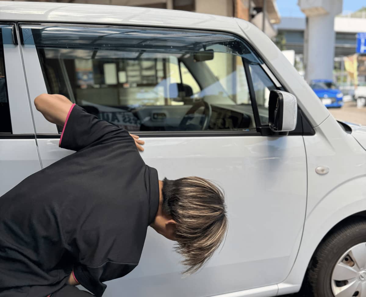 白い車の側面を丁寧に点検しているスタッフ