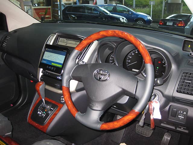 ウッド調のハンドルとシフトノブが特徴のトヨタ車の運転席。