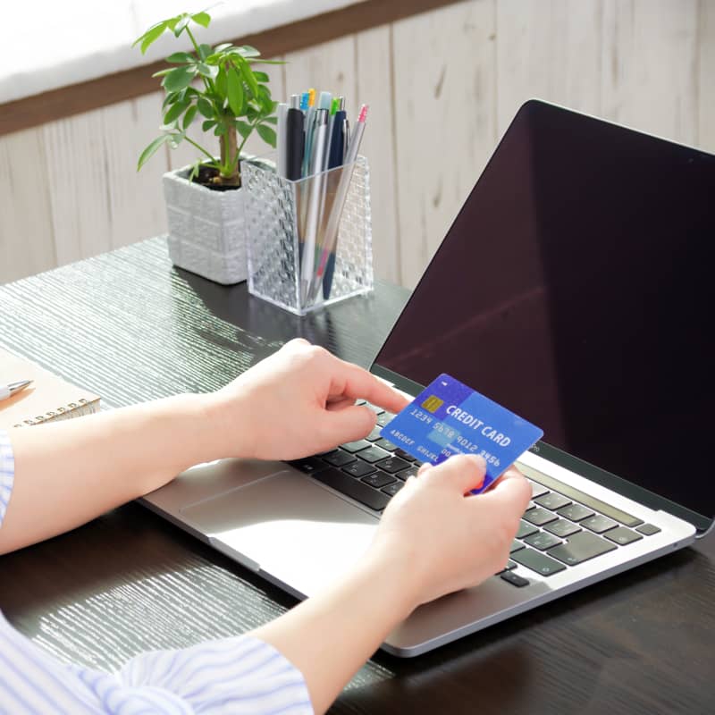 ノートパソコンにクレジットカードを入力しようとしている人の手元